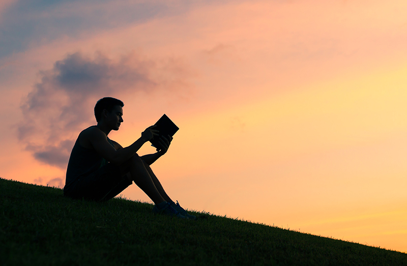 夕暮れ時に一人読書する男性