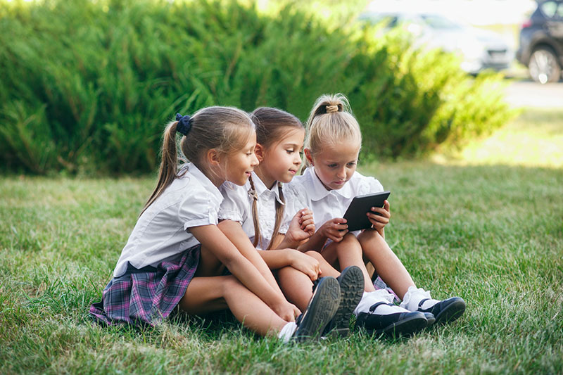 芝生で電子書籍を見る女の子達