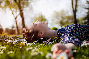 笑顔で芝生の上に寝転がる女性