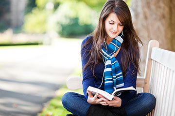 公園のベンチで本を読む女性
