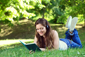 ヘッドホンで音楽を聴きながら読書する女性